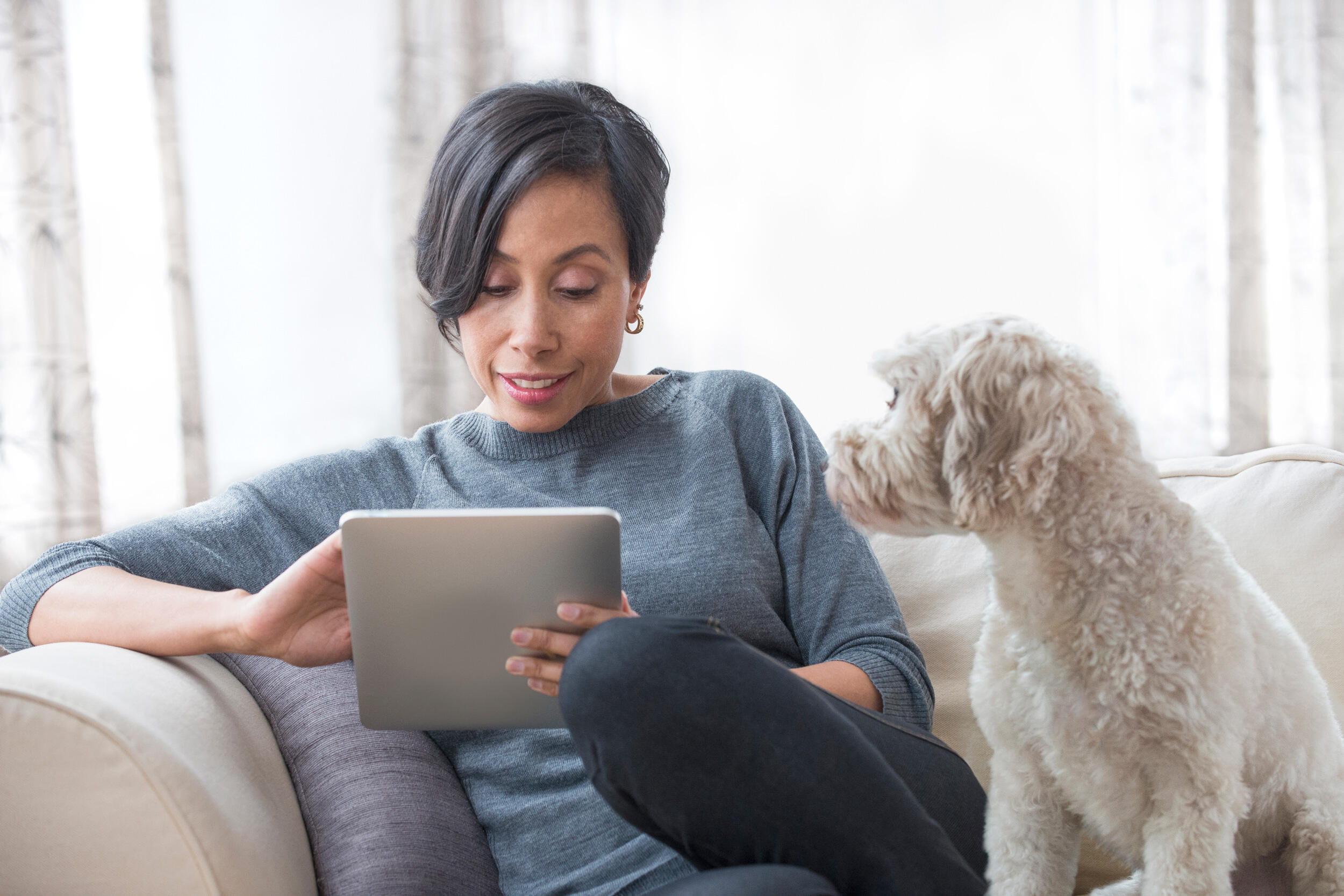 women looking at tablet with dog next to her